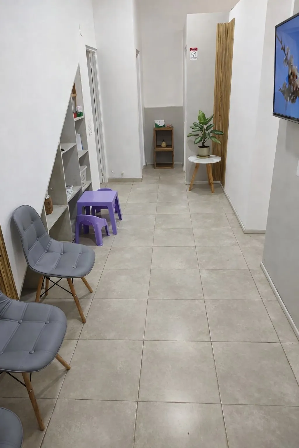 Sala de espera con sillas para adultos y una mesita con sillas para chicos